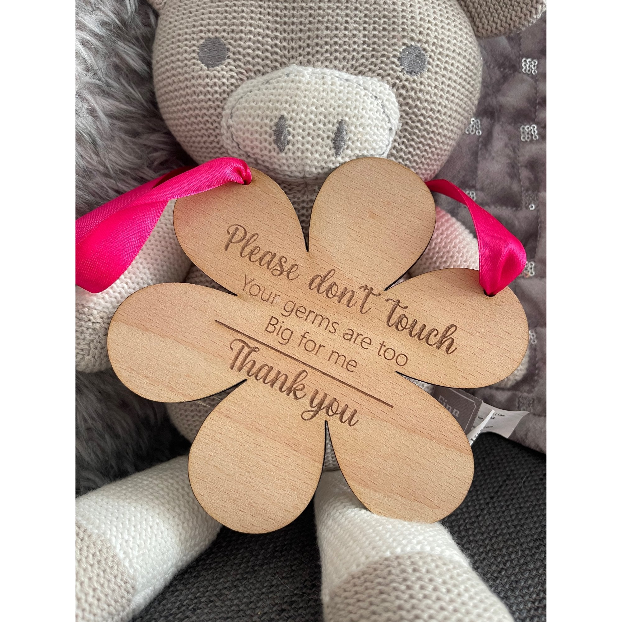 Celebrate motherhood and prioritize your baby's safety with our flower-shaped beech wood hanging sign. Crafted from sturdy 4mm wood and measuring 145mm by 148mm, this enchanting piece is more than decor; it's a protective shield. Engraved with 'Please do not touch, your germs are too big for me, thank you,' and available with a charming blue or pink ribbon.