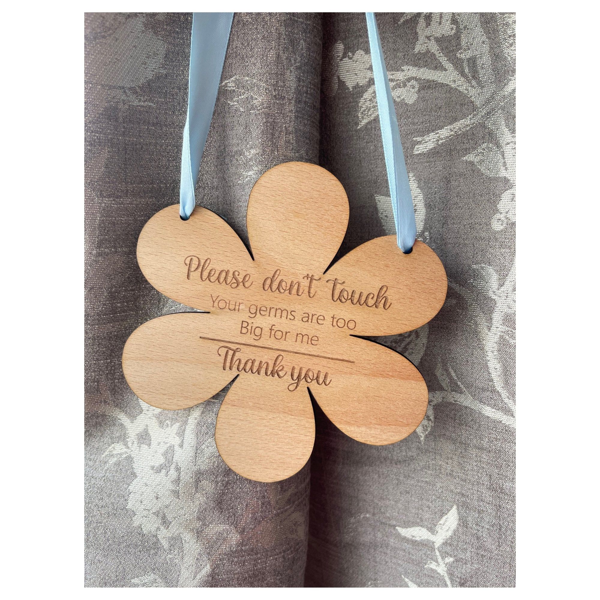 Celebrate the journey of motherhood with our protective flower-shaped beech wood hanging sign. Crafted from sturdy 4mm wood and measuring 145mm by 148mm, this enchanting piece transcends mere decor. Engraved with 'Please do not touch, your germs are too big for me, thank you,' and available with a touch of personalization through your choice of blue or pink ribbon.