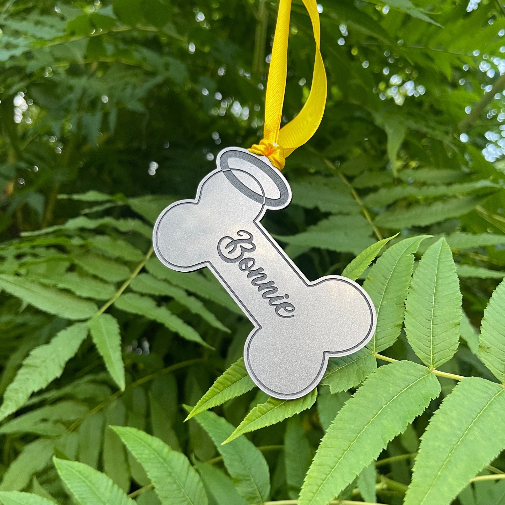 Customizable Dog Memorial Hanging Bone: A yellow ribbon-adorned, 3mm thick acrylic bone with black engraved details and a halo. Create a lasting tribute to your beloved dog by personalizing the bone with their name. A heartfelt and enduring way to honor your furry companion.