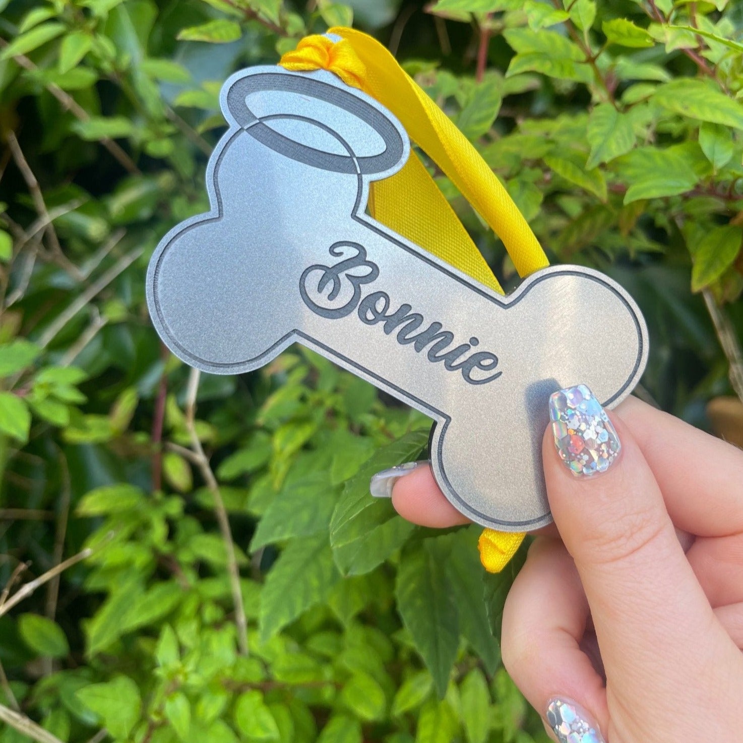 Personalised Dog Remembrance Hanging Bone | Halo: A heartfelt tribute to your furry companion. This keepsake features a yellow hanging ribbon and elegant black engraving. Crafted from durable 3mm thick acrylic, the halo-shaped bone is personalized with your beloved pet's name, ensuring lasting memories. A cherished memento to honor your faithful friend.