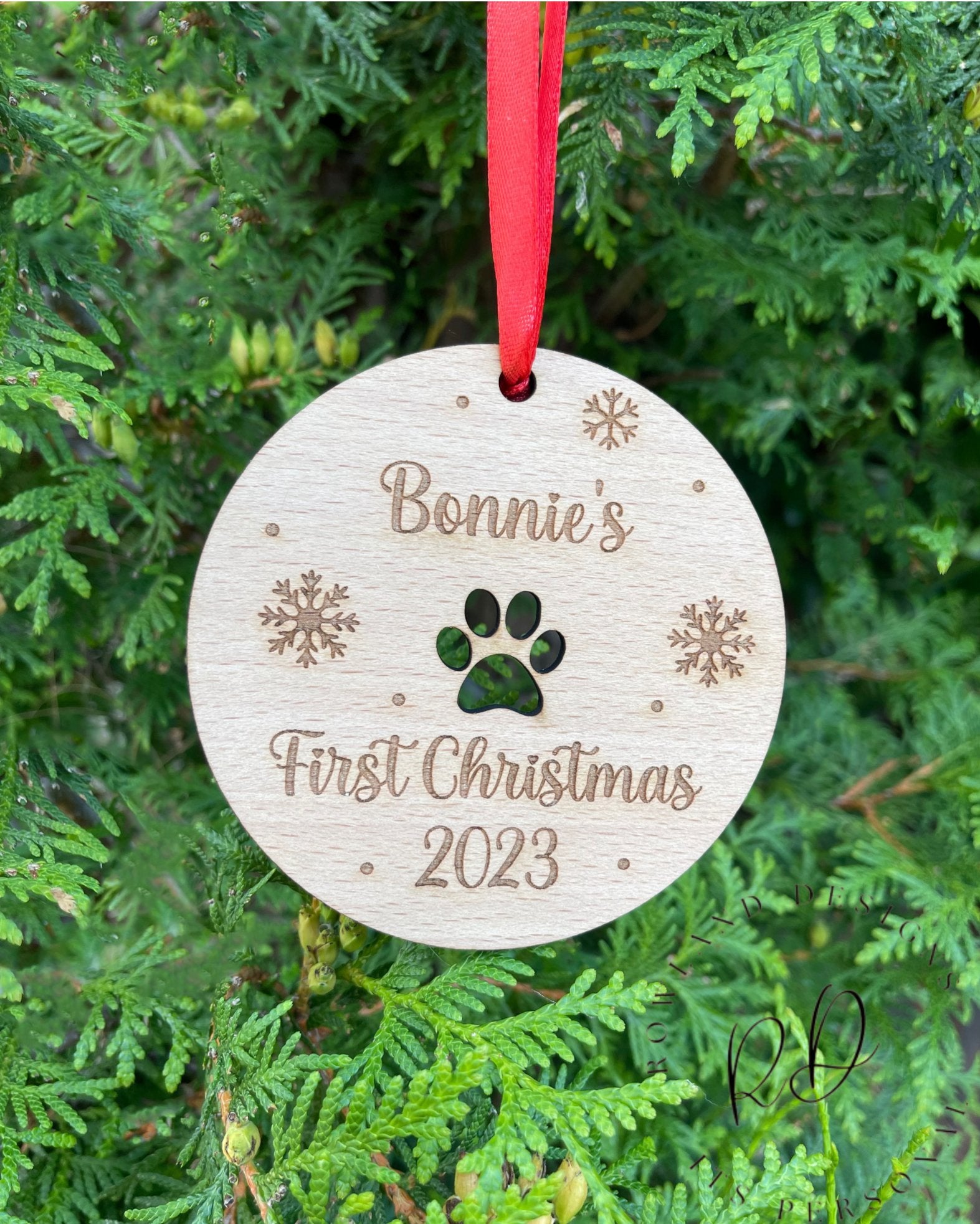 Personalised Wooden Paw Print Christmas Bauble with Name Engraving, Snowflakes, and 'First Christmas' Inscription