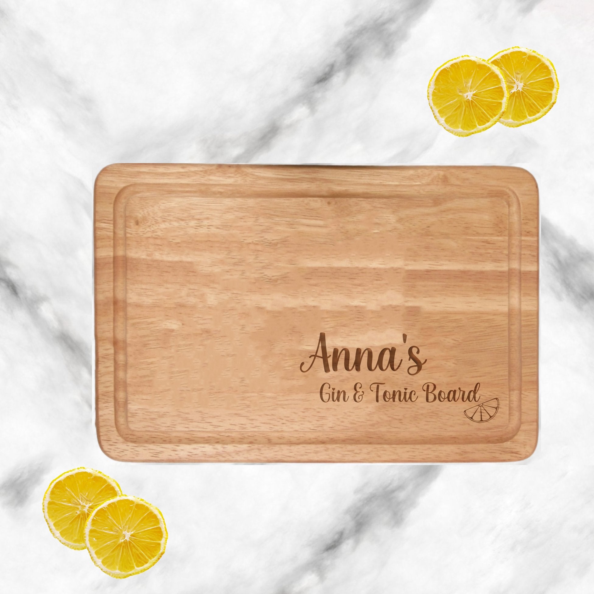 Image Description: A personalised Chopping board G&T crafted from high-quality wood. Engraved with a custom name, it serves as a unique and stylish personalised birthday or housewarming personalised gift for her. The board features a standard message 'Gin & Tonic Board with Engraved Lemon,' adding an extra touch of charm to any kitchen.