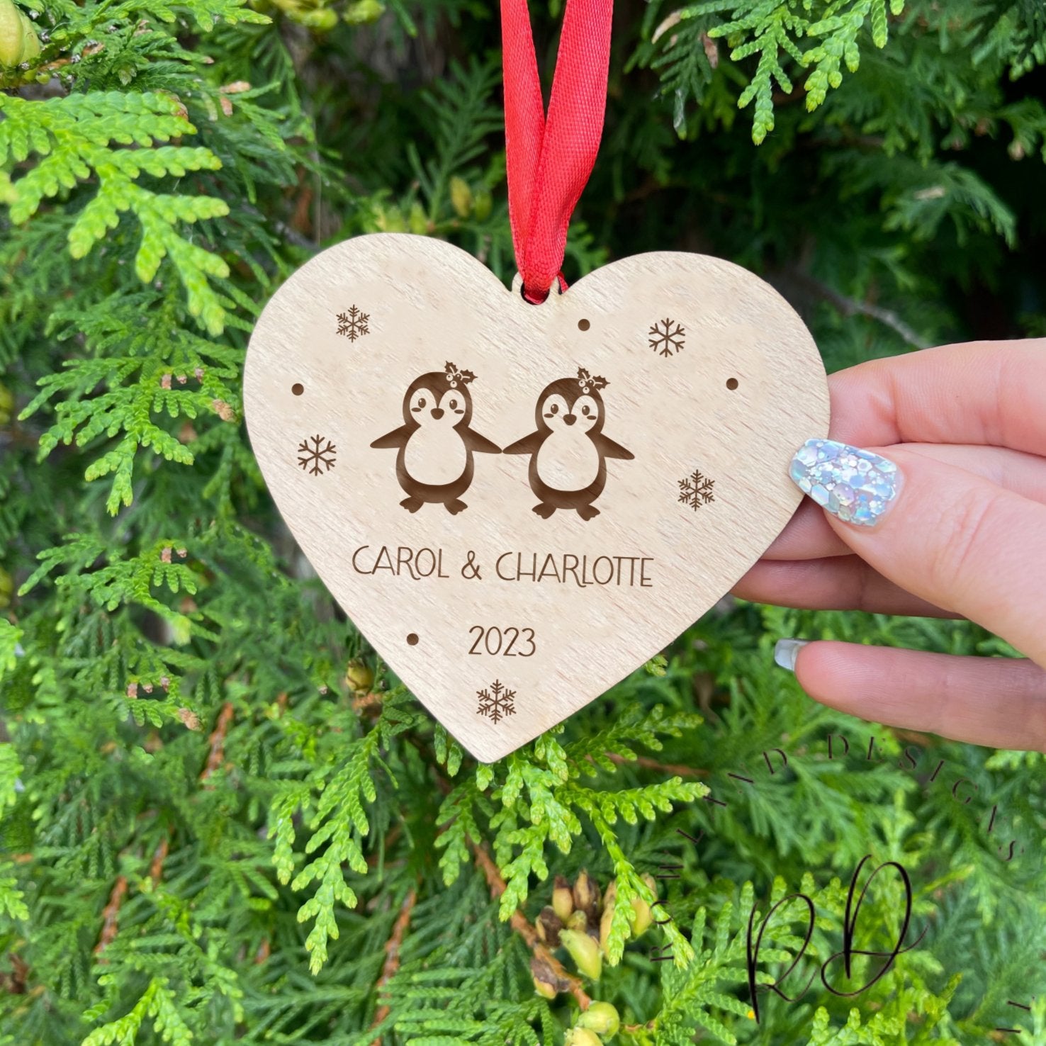 Custom Wooden Heart-Shaped Christmas Bauble with Interlocking Penguins, Snowflakes, Personalized Engravings, and Red Ribbon. Perfect Holiday Decor and Gift for Couples. 🎄🎅