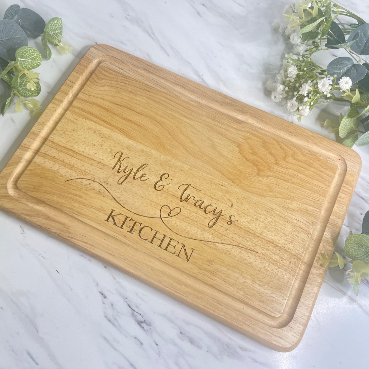Personalised Engraved Wooden Chopping Board, personalise you5r chopping board with a name on the left and side and name on the right,  underneath is a heart then the word kitchen at the bottom. This is make from  Hevea Wood & the size is 300mmX200mm. Perfect gift for any couple. 
