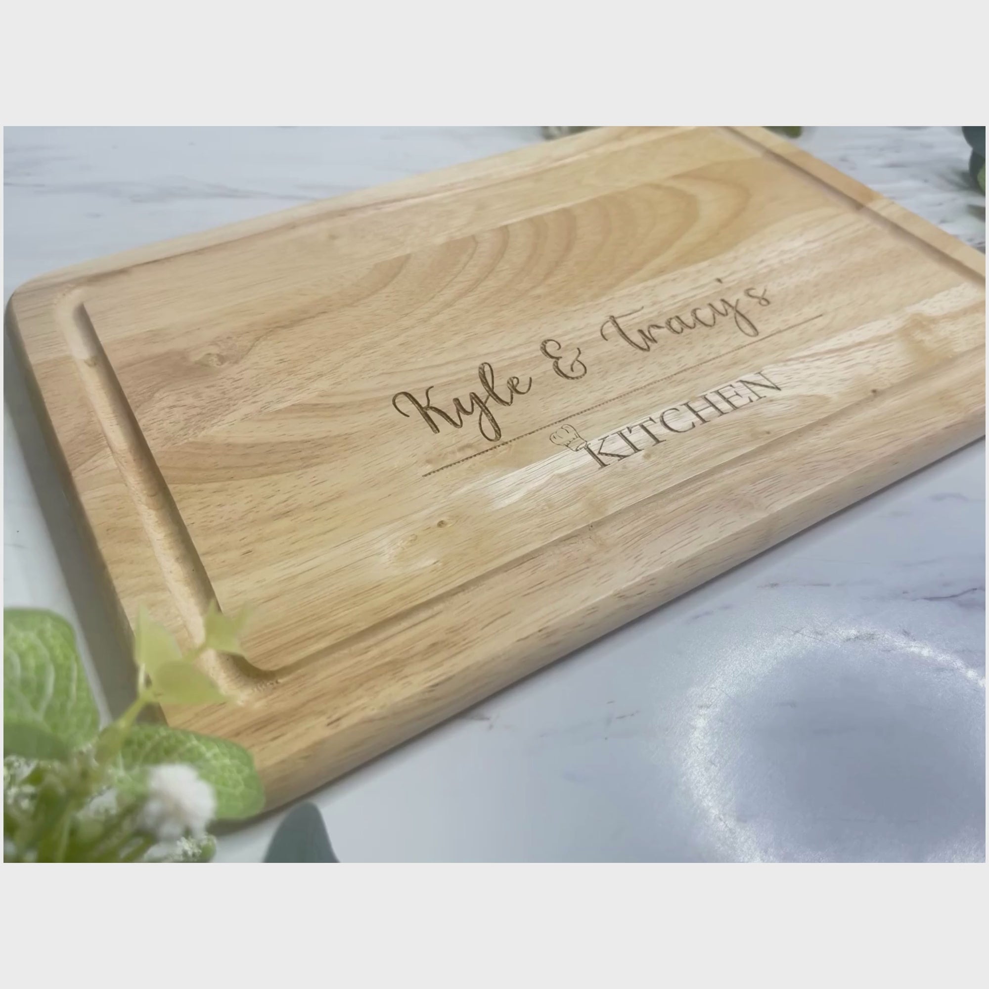 Personalised Engraved Wooden Chopping Board, personalise your chopping board with a name on the left and side and name on the right,  underneath is a line then at the bottom the word kitchen with a little chefs hat above the K. This is make from  Hevea Wood & the size is 300mmX200mm. Perfect gift for any couple. 