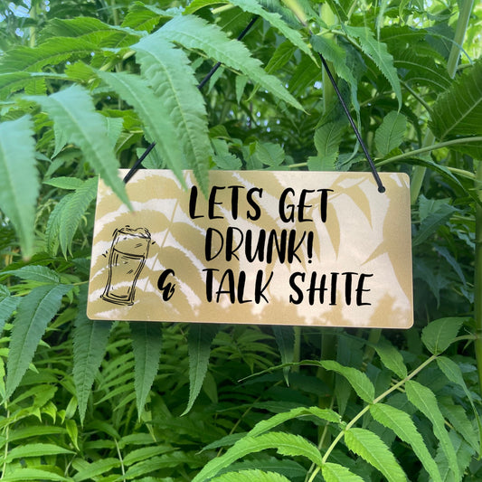 Humorous engraved sign that says 'Let's get drunk & talk shite' on a silver or gold acrylic background. With beer icon 
