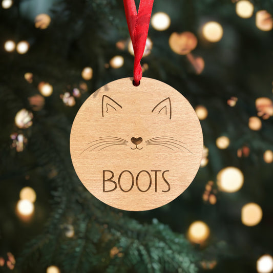 Wooden cat Christmas bauble with personalised name, ears, nose, mouth, and whiskers details. Crafted from 4mm beech veneer wood with a classic red ribbon, a heartfelt addition to your holiday tree.