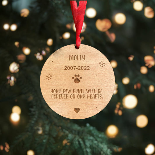Personalised Dog Remembrance Hanging Decoration - Handcrafted from premium beech veneer, this round 4mm thick decoration features your pet's name, a paw print, heart. The message reads, 'Your paw print will be forever on our hearts.' 100mm x 100mm.