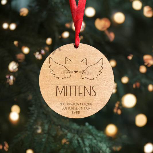  Wooden memorial cat bauble with personalised name, ears, nose, mouth, and whiskers details. Crafted from 4mm beech veneer wood with a red ribbon, perfect for your holiday tree.