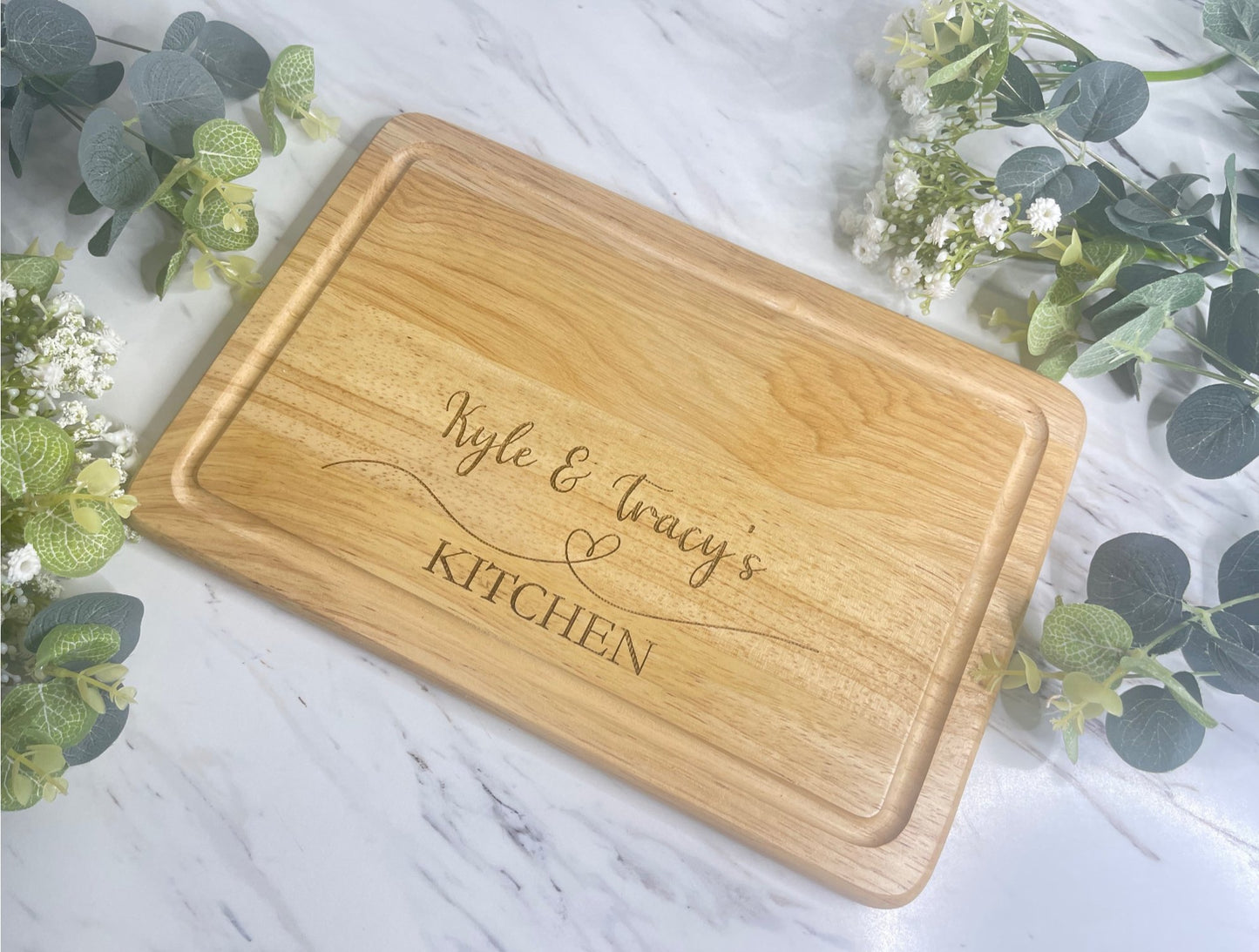 Personalised Engraved Wooden Chopping Board, personalise you5r chopping board with a name on the left and side and name on the right,  underneath is a heart then the word kitchen at the bottom. This is make from  Hevea Wood & the size is 300mmX200mm. Perfect gift for any couple. 
